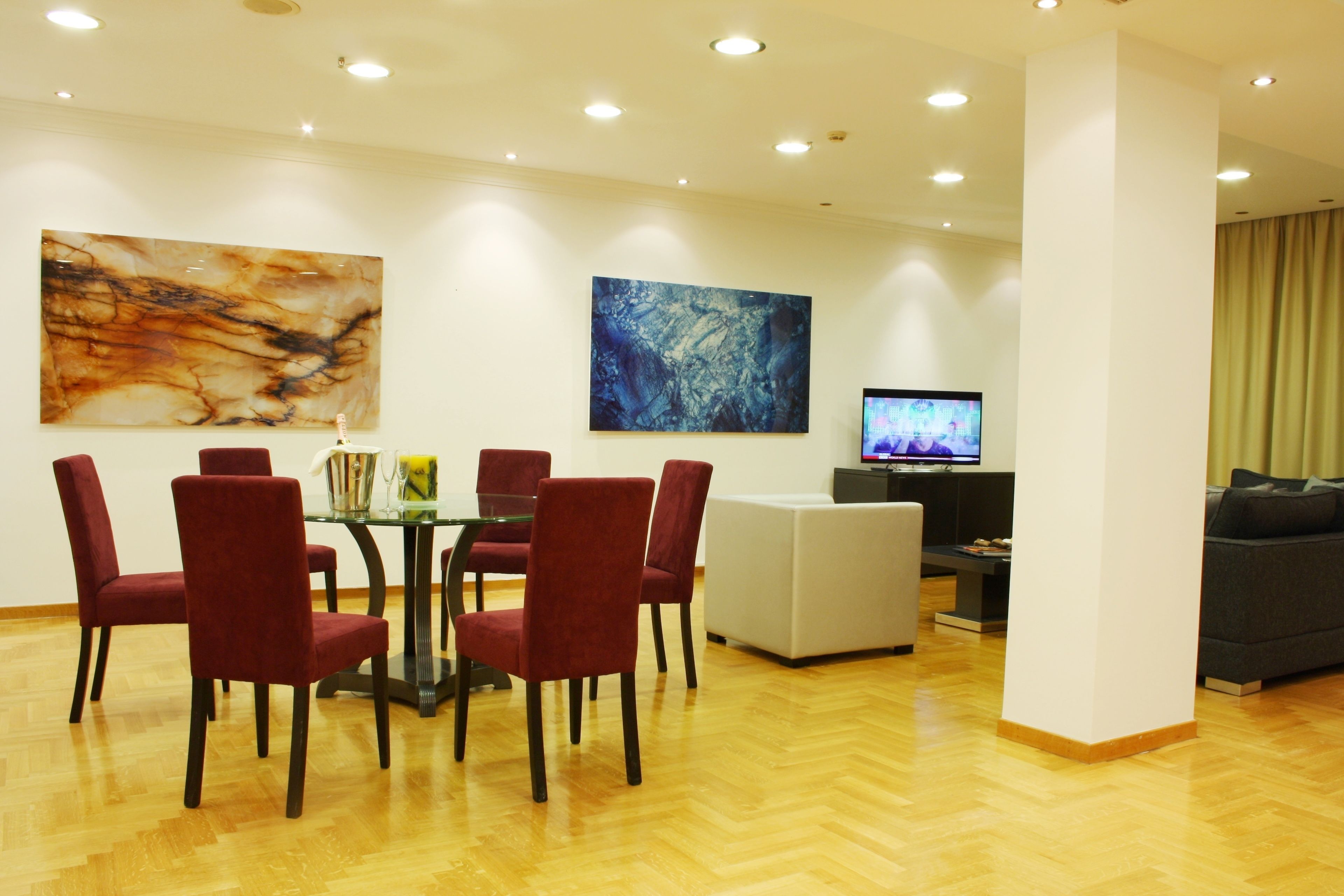 A modern living room with a dining area, a flat-screen TV, and abstract art on the walls.