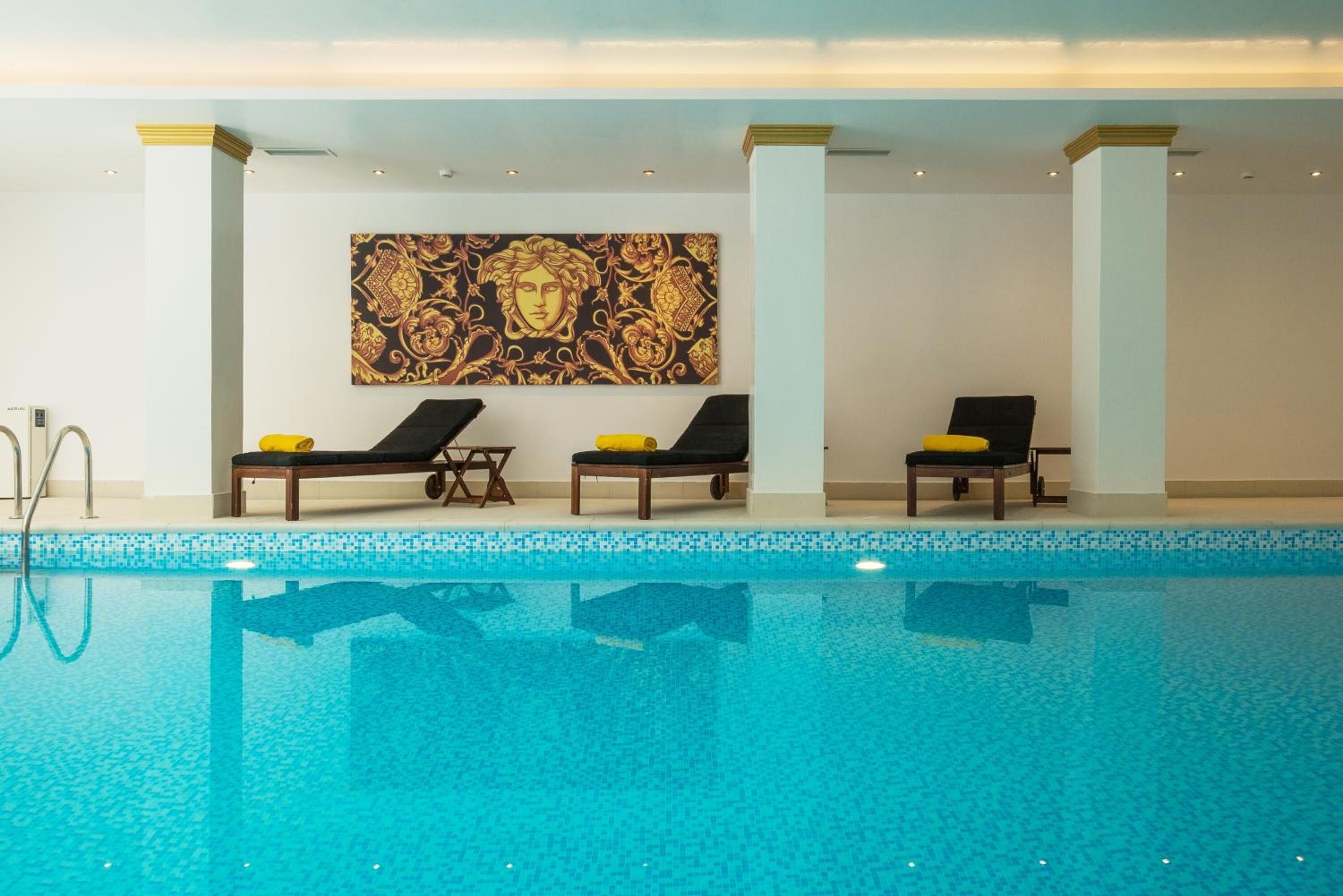 Una piscina con sillones de descanso y un gran muro decorativo.