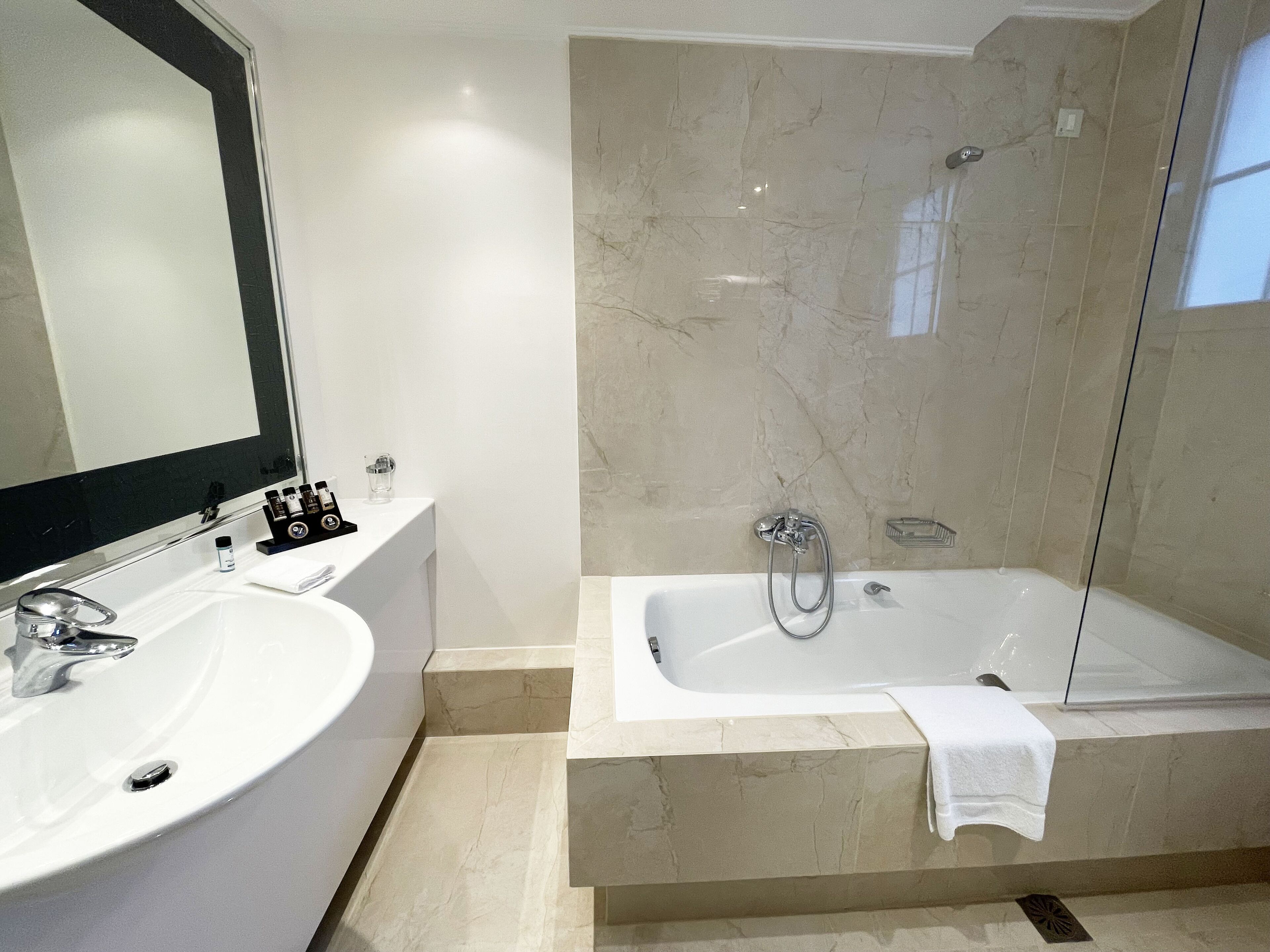 A modern bathroom with a large sink, mirror, and a walk-in shower.