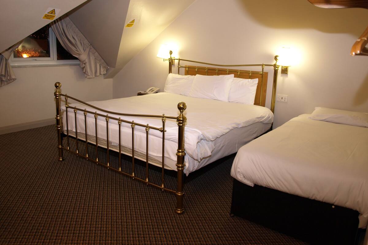 A bedroom with a single bed, a smaller bed, and a nightstand with a phone.