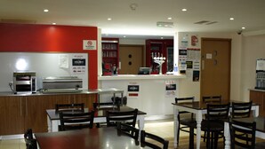 Ein Hotelrestaurant mit Theke, Sitzbereich und Küche.