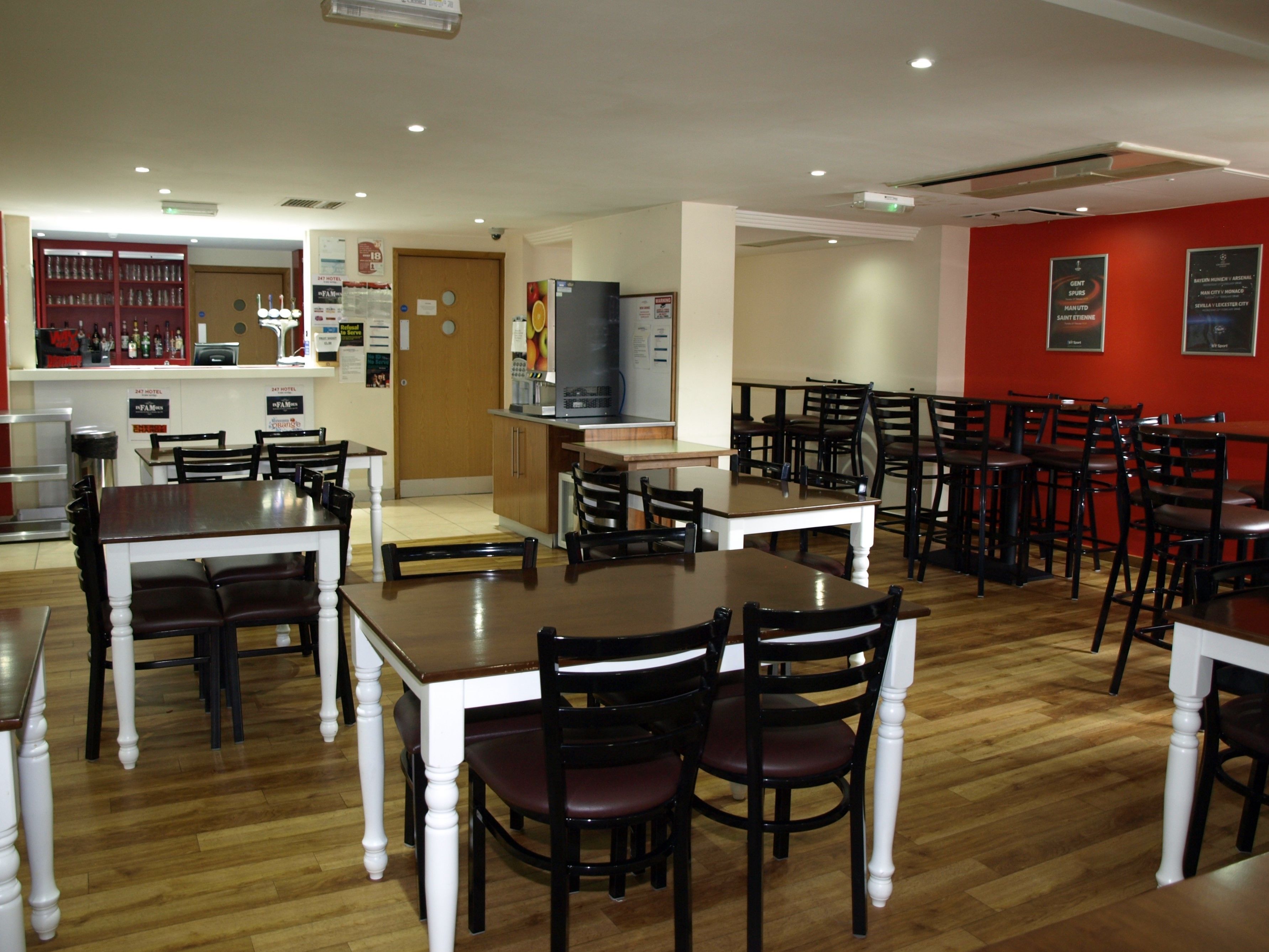 Un restaurante con varias mesas y sillas, una zona de bar y un refrigerador.
