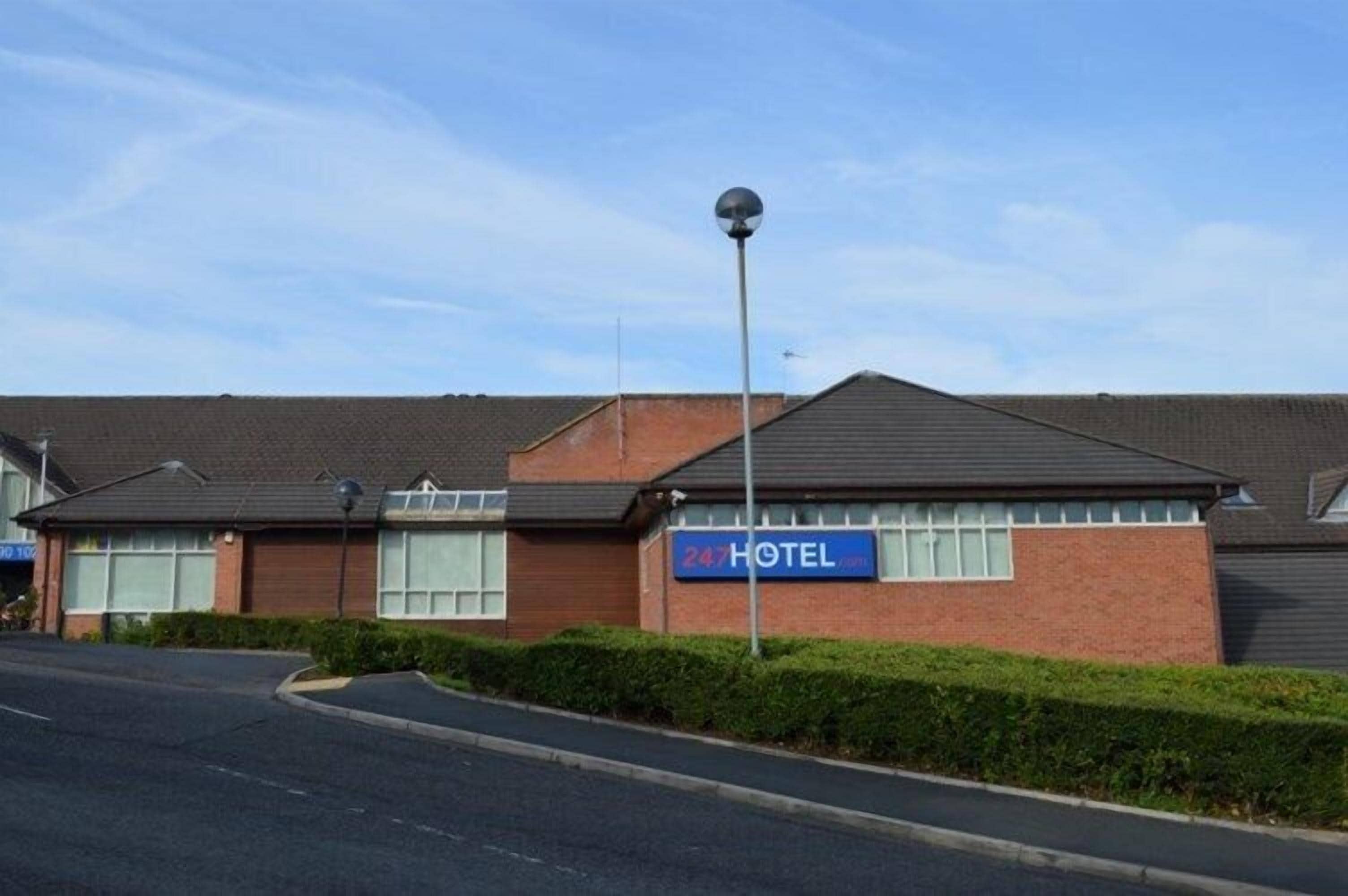 A hotel with a sign reading "247 HOTEL" and a street lamp in front.