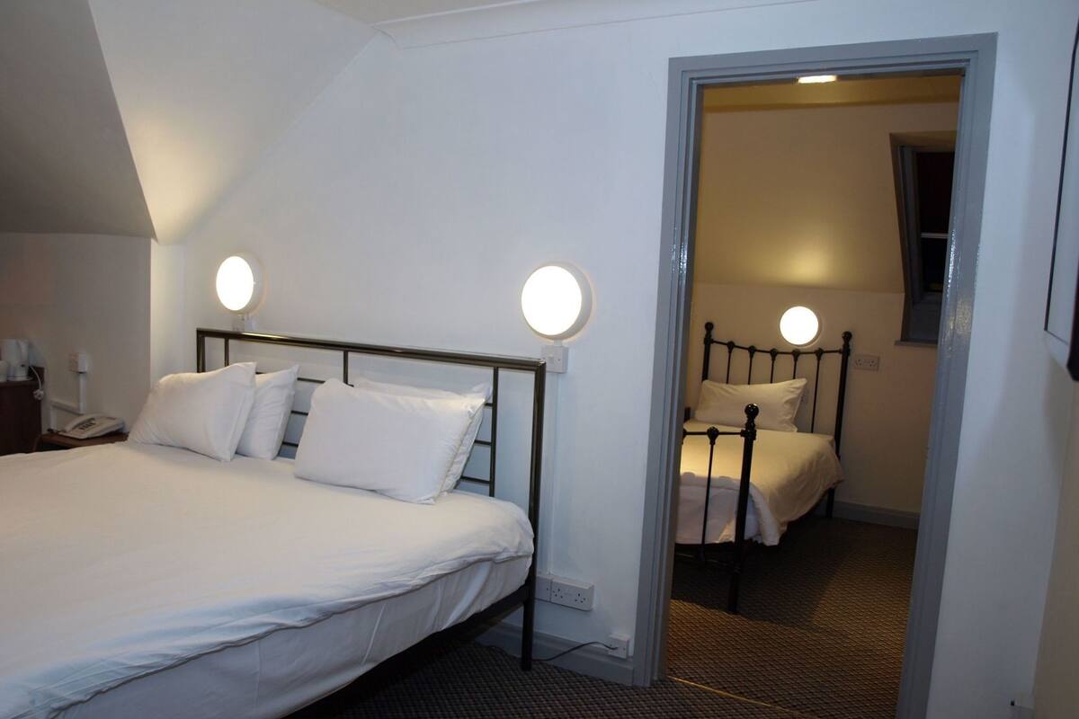 A hotel room with a large bed, bedside lamps, a telephone, and a carpeted floor.