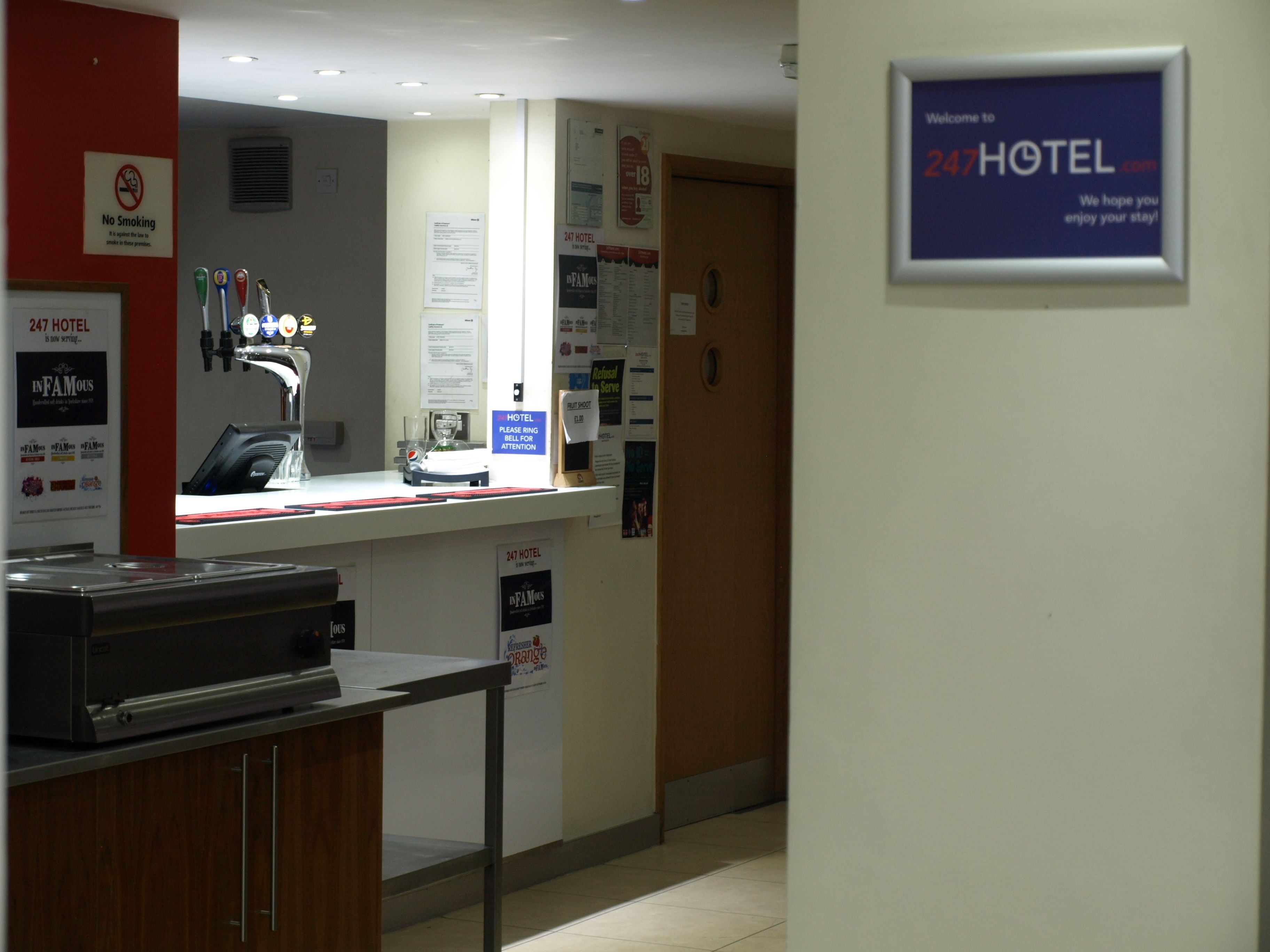 A hotel reception area with a counter, a no smoking sign, and a welcome sign.
