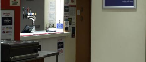 A hotel reception area with a counter, a no smoking sign, and a welcome sign.
