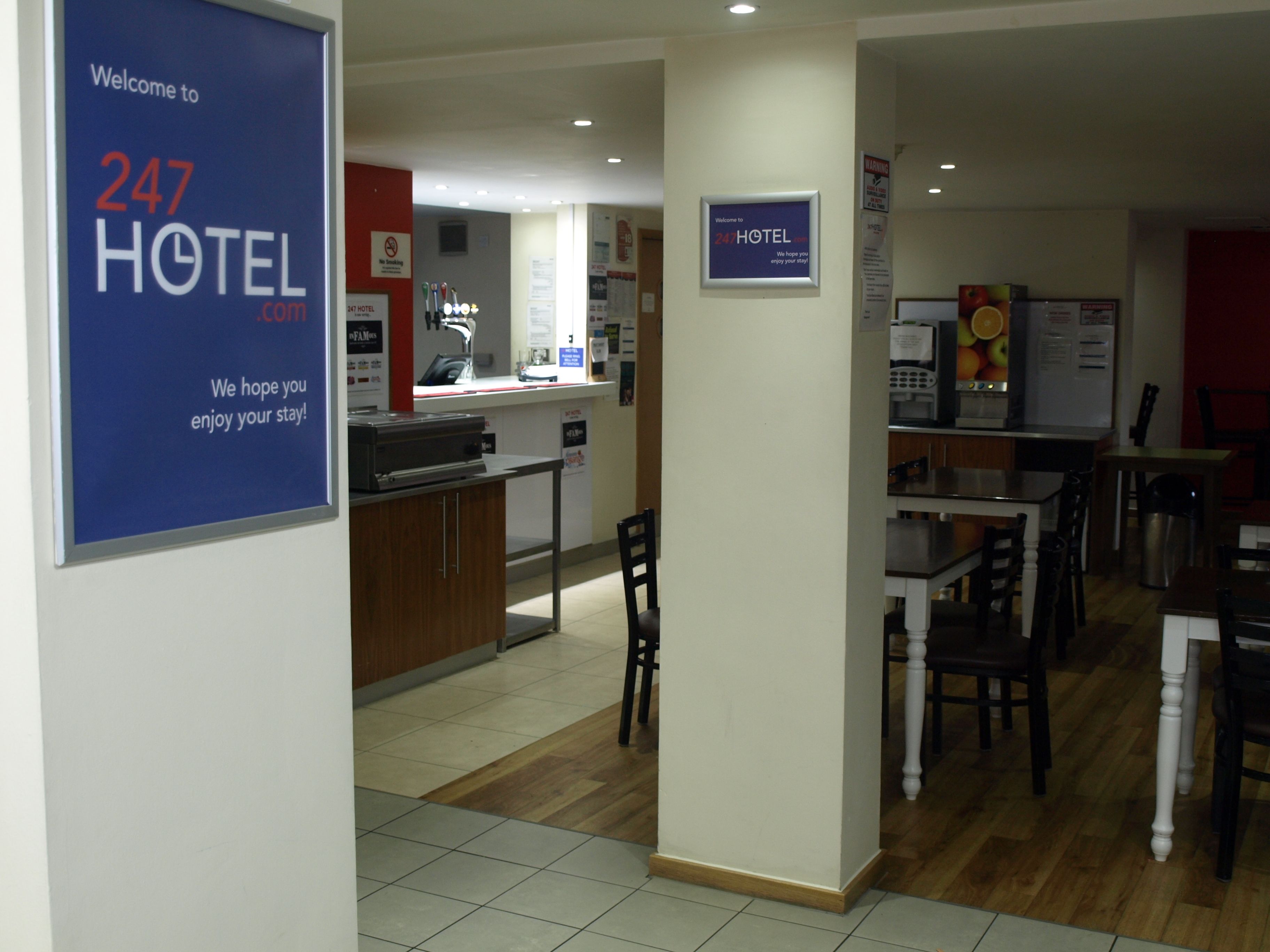 Un vestíbulo de hotel con una recepción, un comedor y una cocina al fondo.