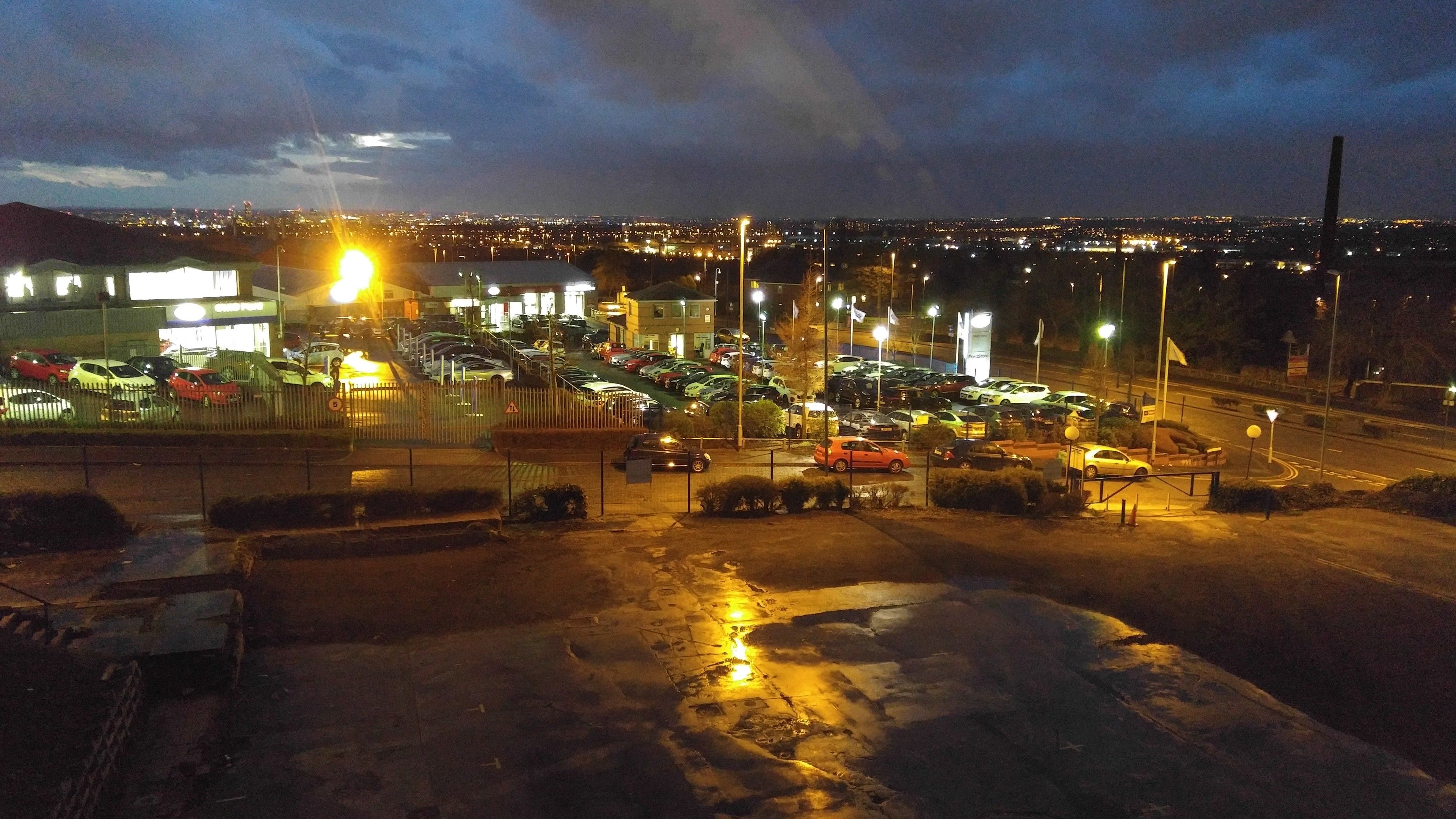 A parking lot with multiple cars and a building in the background.