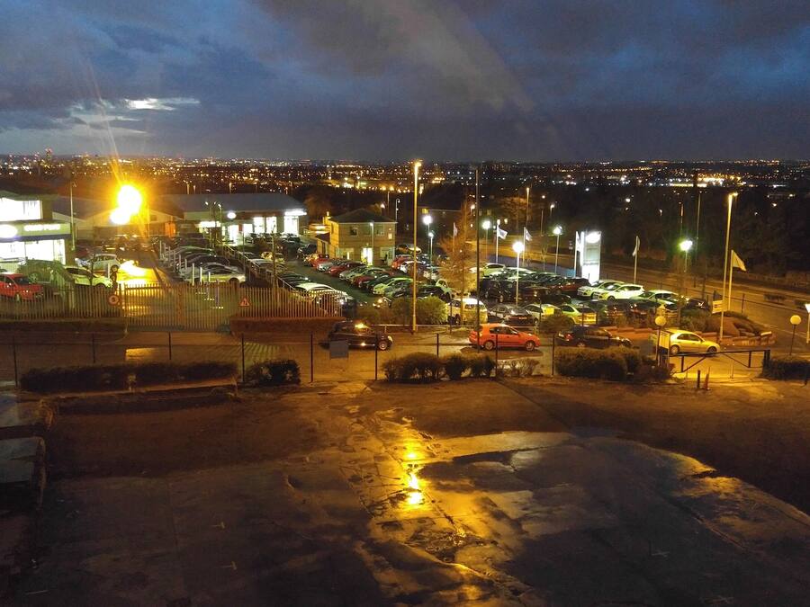 Een parkeerplaats met meerdere auto's en een gebouw op de achtergrond.