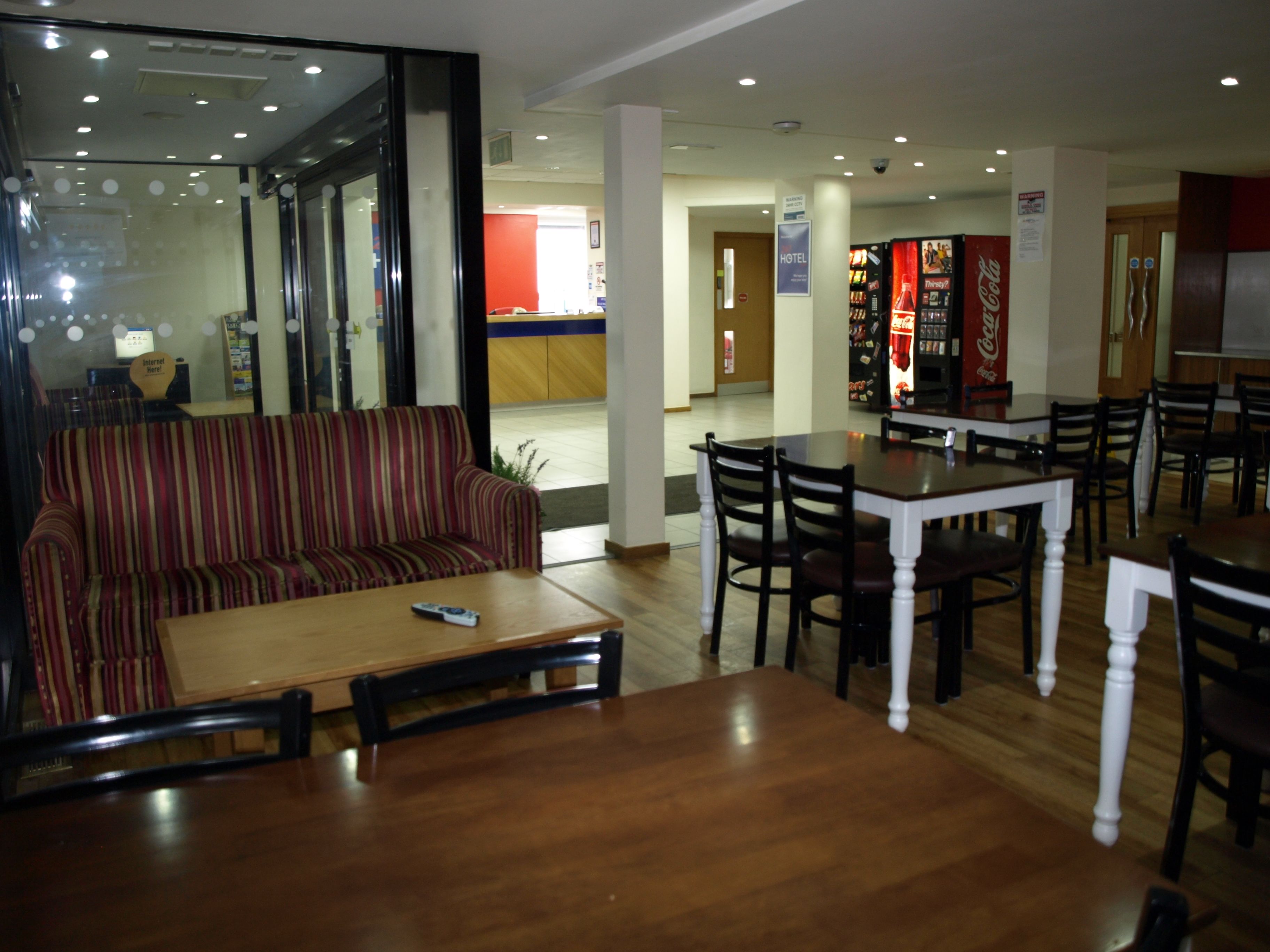 A hotel dining area with a striped sofa, wooden tables, and chairs.