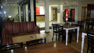 A hotel dining area with a striped sofa, wooden tables, and chairs.