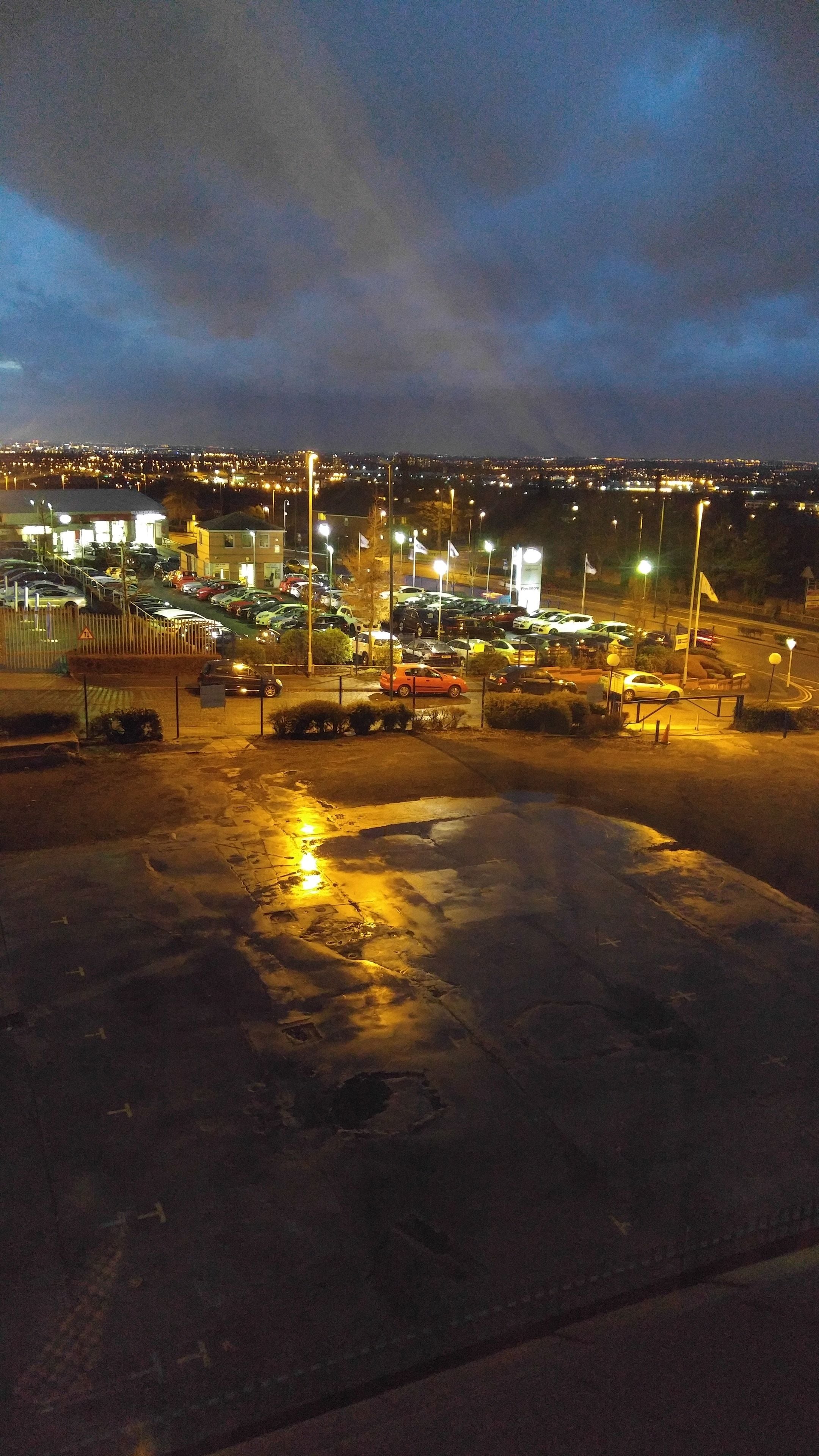 Un parking avec plusieurs voitures et un bâtiment en arrière-plan.