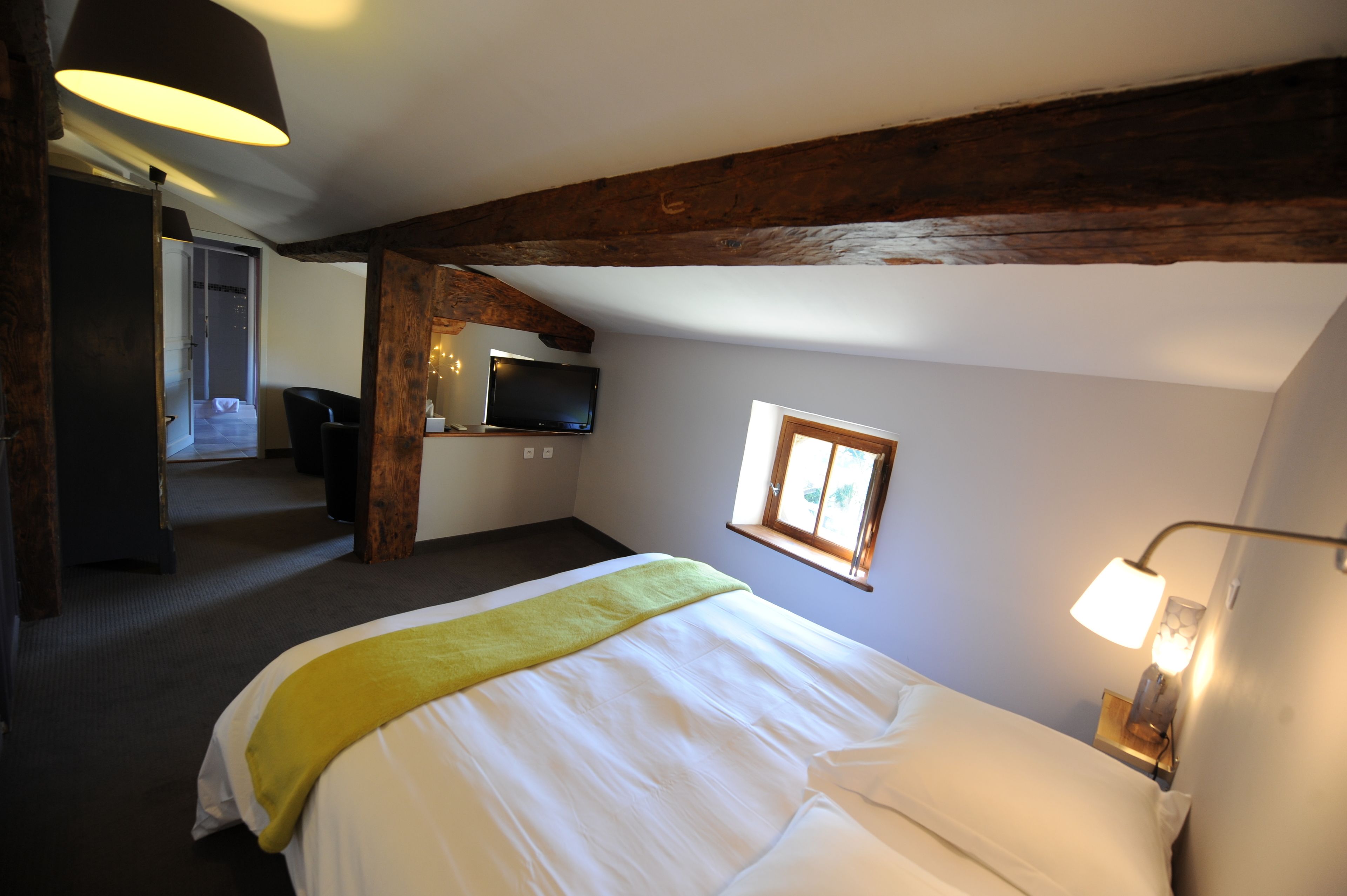 Una habitación de hotel con cama, televisión, ventana y lámpara.