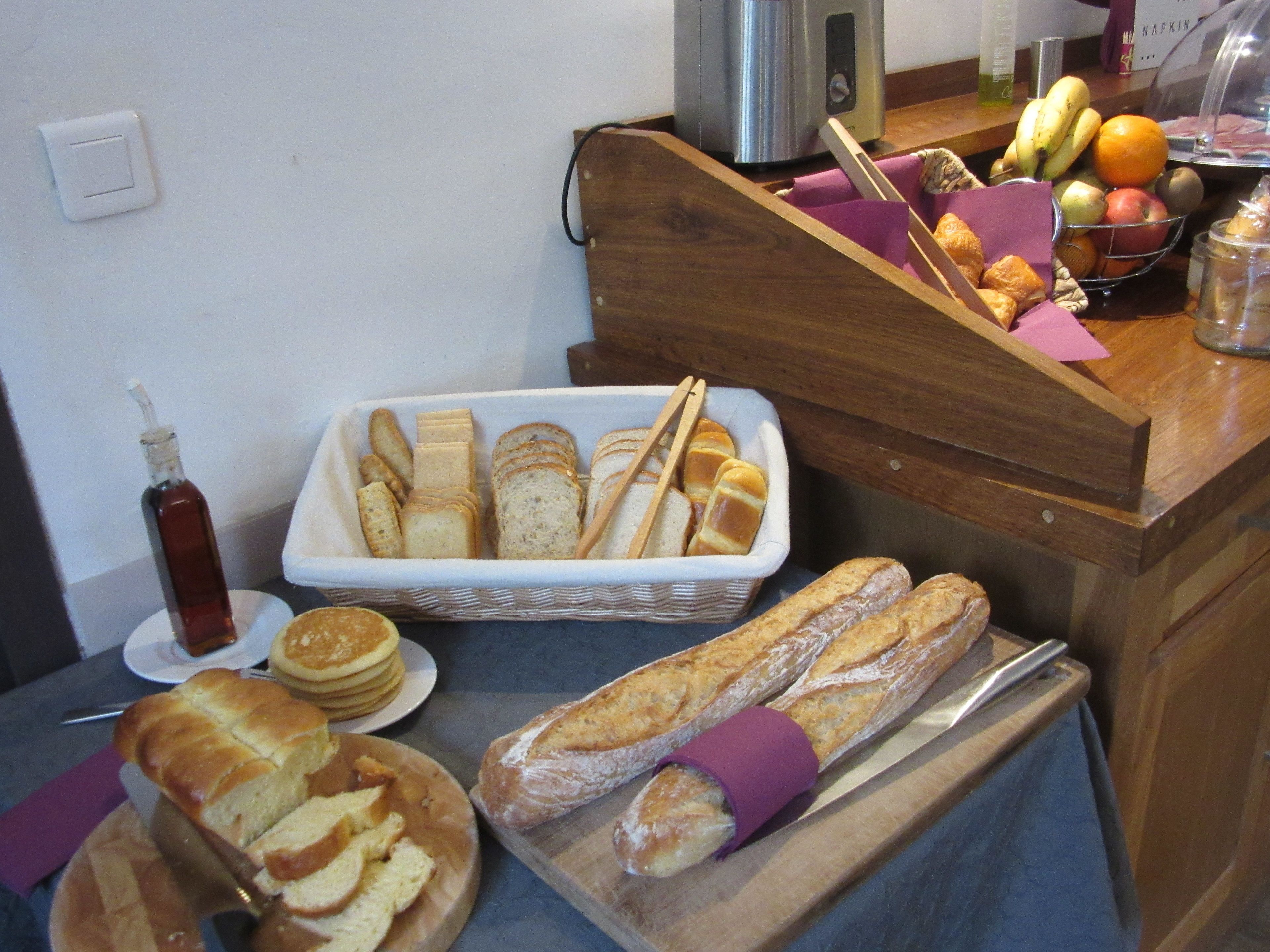A breakfast buffet with bread, pastries, and fruits.