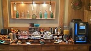 A breakfast buffet with various food items, a coffee machine, and decorative bottles on shelves. - Hotel Château de Palaja (Palaja)