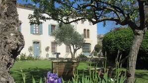 A white building with blue shutters, a tree in the foreground, and a purple flower. - Hotel Château de Palaja (Palaja)