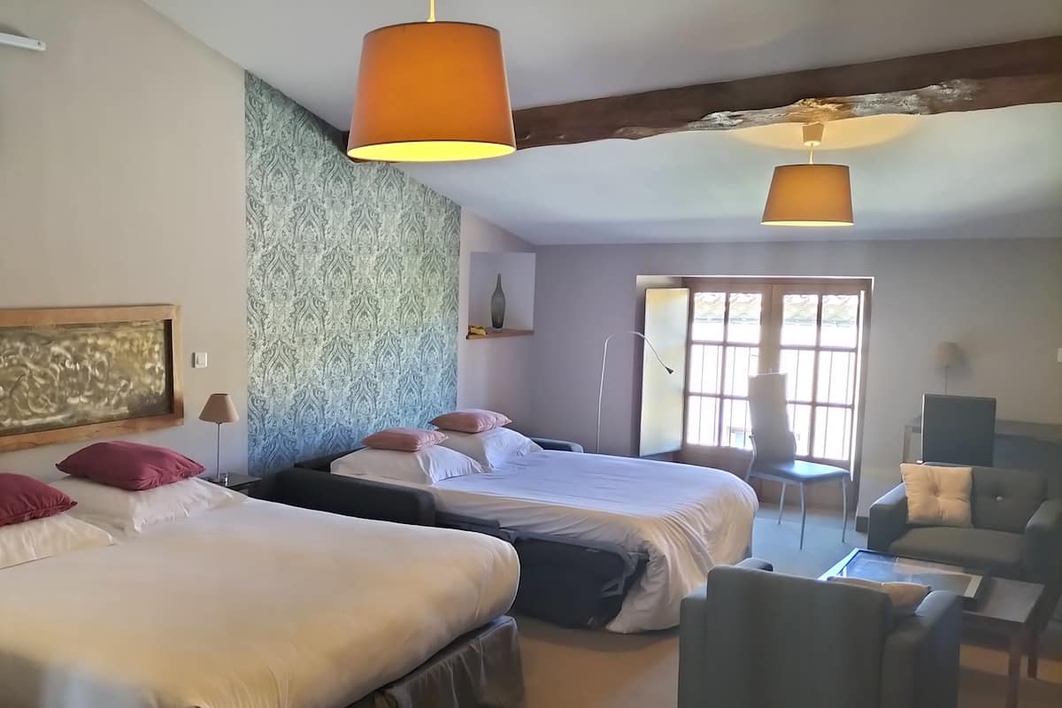 A hotel room with two beds, a large window, a ceiling fan, and a TV.