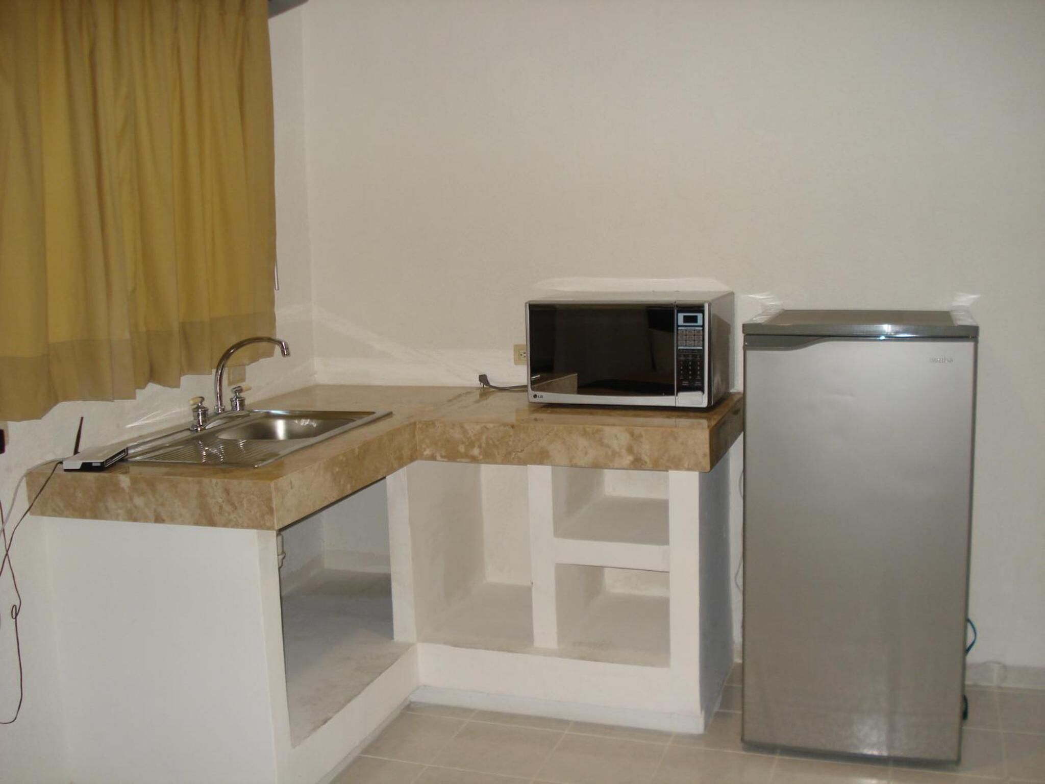 Una cocina compacta con un lavamanos, un microondas y un refrigerador.
