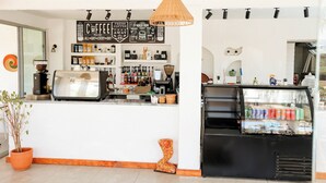 A coffee shop interior with a counter, coffee machines, shelves with coffee products, and a refrigerated display. - Marin-A Hotel (Bodrum)