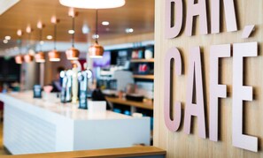 A modern cafe interior with a wooden counter and hanging pendant lights. - Travelodge London Vauxhall (London)