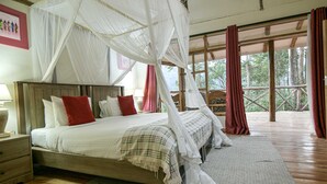 A bedroom with a canopy bed, wooden flooring, and a view of the outdoors. - Gorilla Safari Lodge (Bwindi)