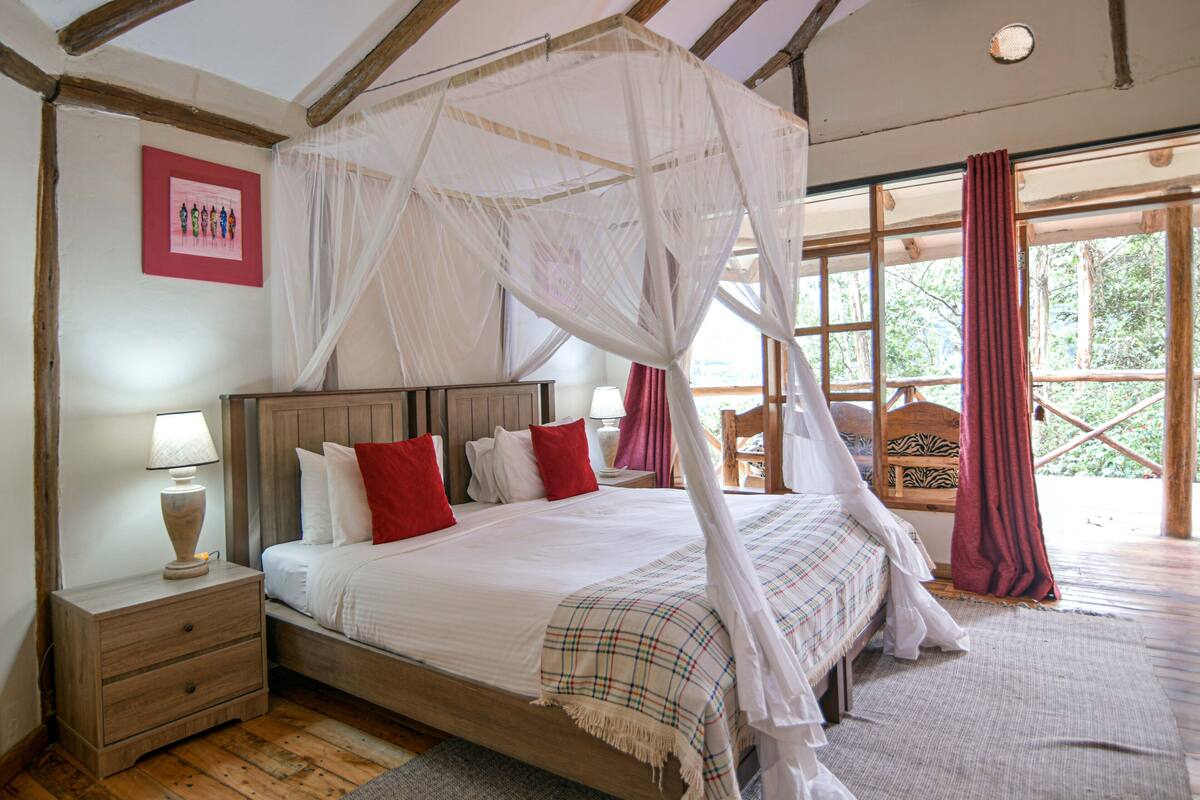 A bedroom with a four-poster bed, wooden headboard, and a nightstand with a lamp.