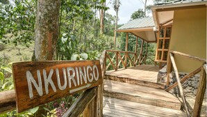 A wooden deck with a sign reading "NKURINGO" leading to a building with a metal roof. - Gorilla Safari Lodge (Bwindi)