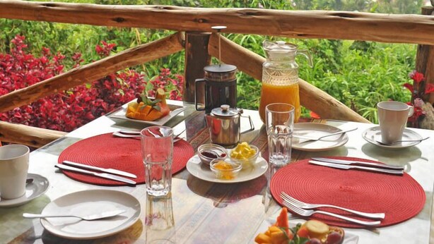 A table set for breakfast with a scenic view of hills and greenery. - Gorilla Safari Lodge (Bwindi)