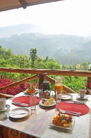 A table set for breakfast with a scenic view of hills and greenery. - Gorilla Safari Lodge (Bwindi)