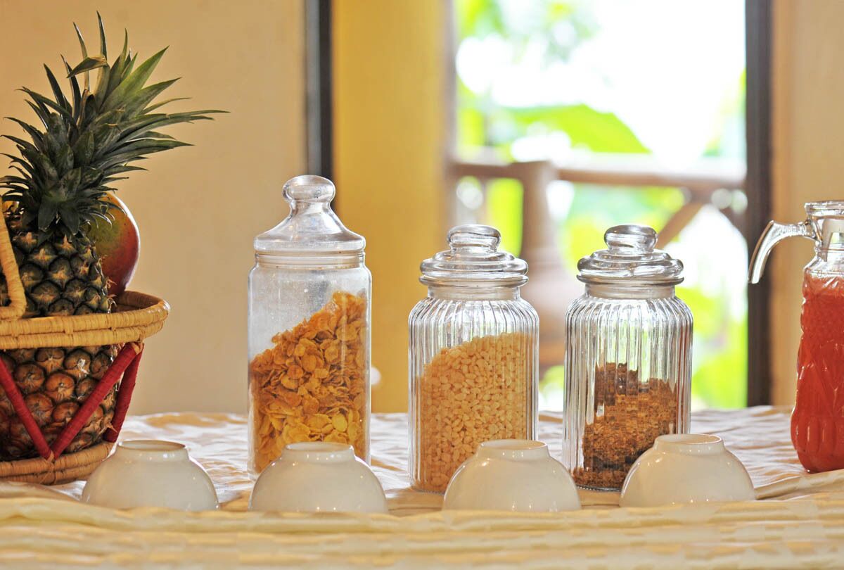 Una mesa con botes de granola y una piña en una cesta.