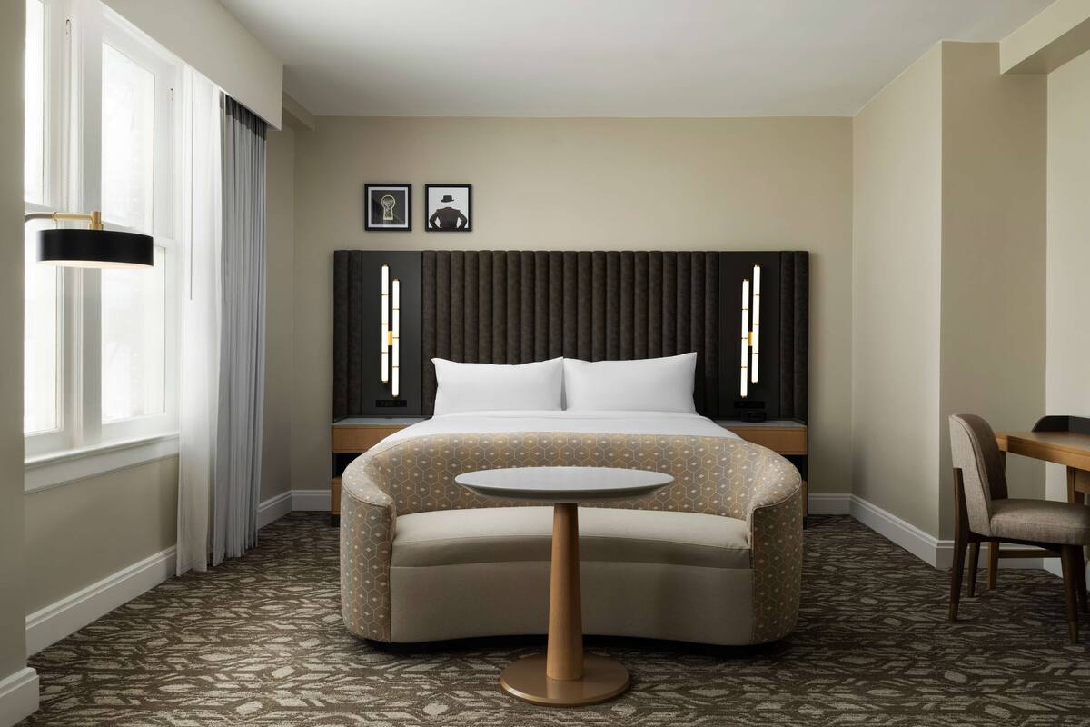 Een hotelkamer met een bed, een ronde tafel, een stoel en een bureau.
