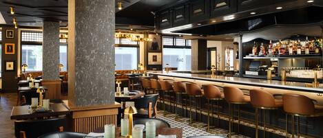 A modern restaurant interior with high tables, bar stools, and a bar area.
