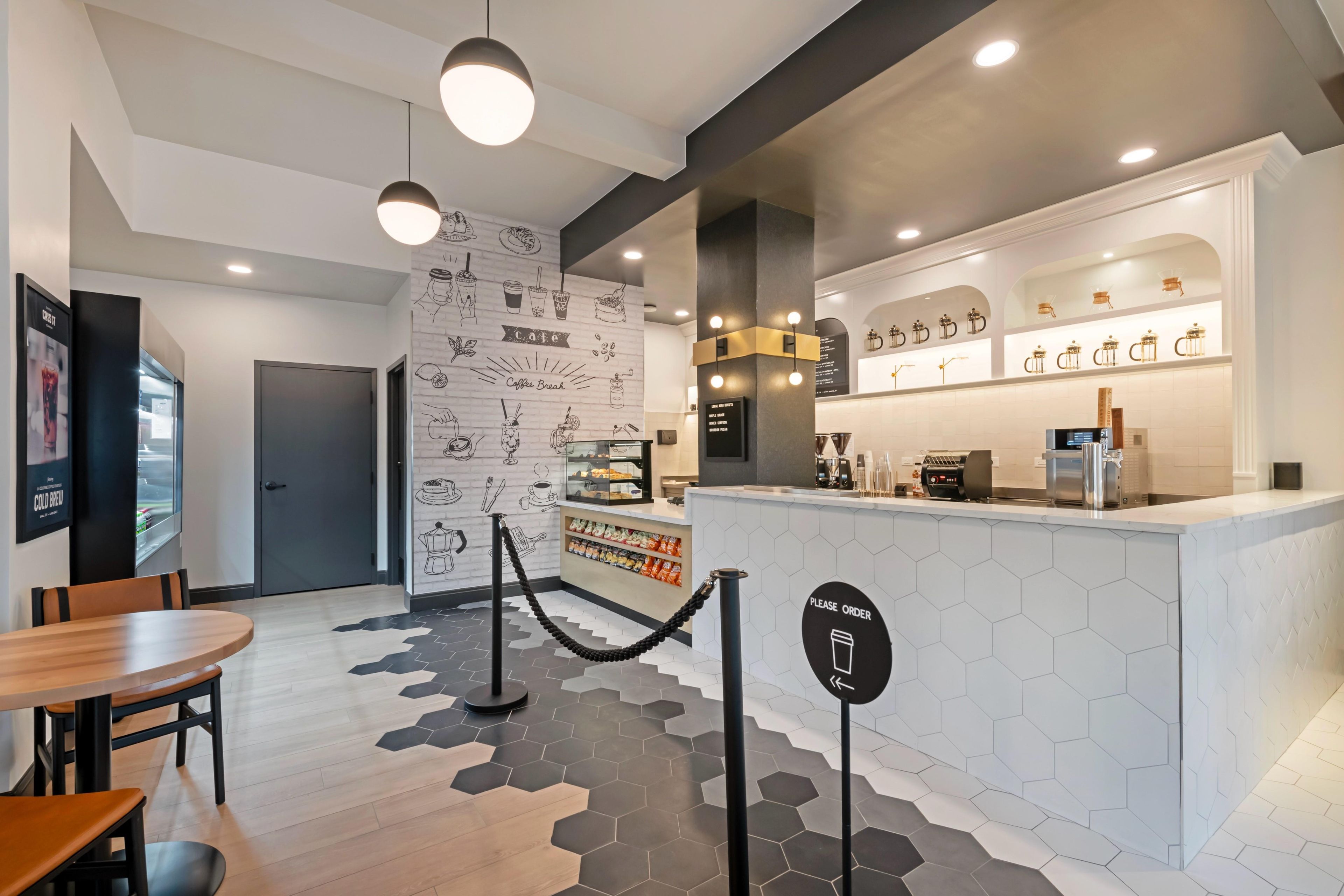 A cafe with a counter, seating area, and a wall with food illustrations.
