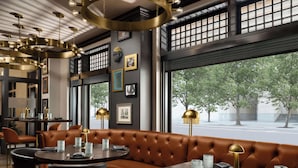Een modern restaurantinterieur met een lederen zithoek, ronde tafels en hanglampen.