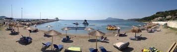 Una playa con tumbonas, sombrillas y una vista despejada del mar.