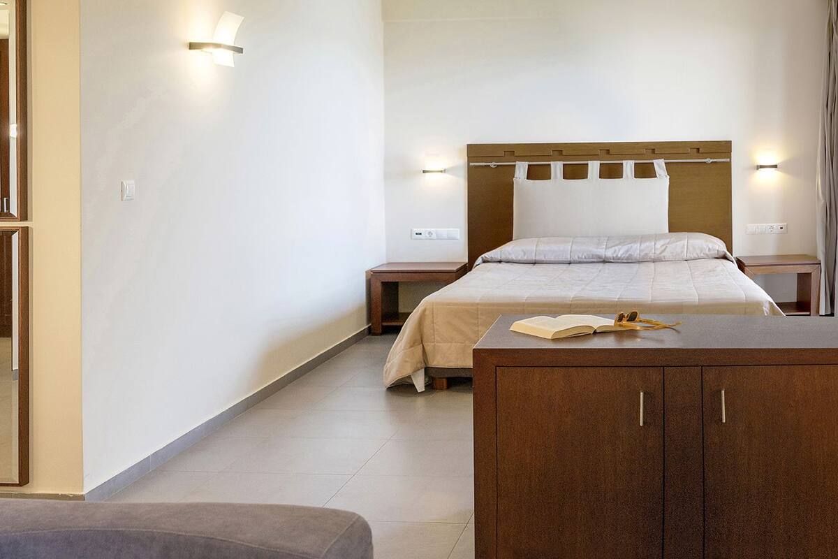Una habitación de hotel con cama, escritorio, silla y armario.
