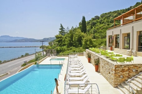 Una piscina al aire libre, sombrillas, sillones reclinables de piscina