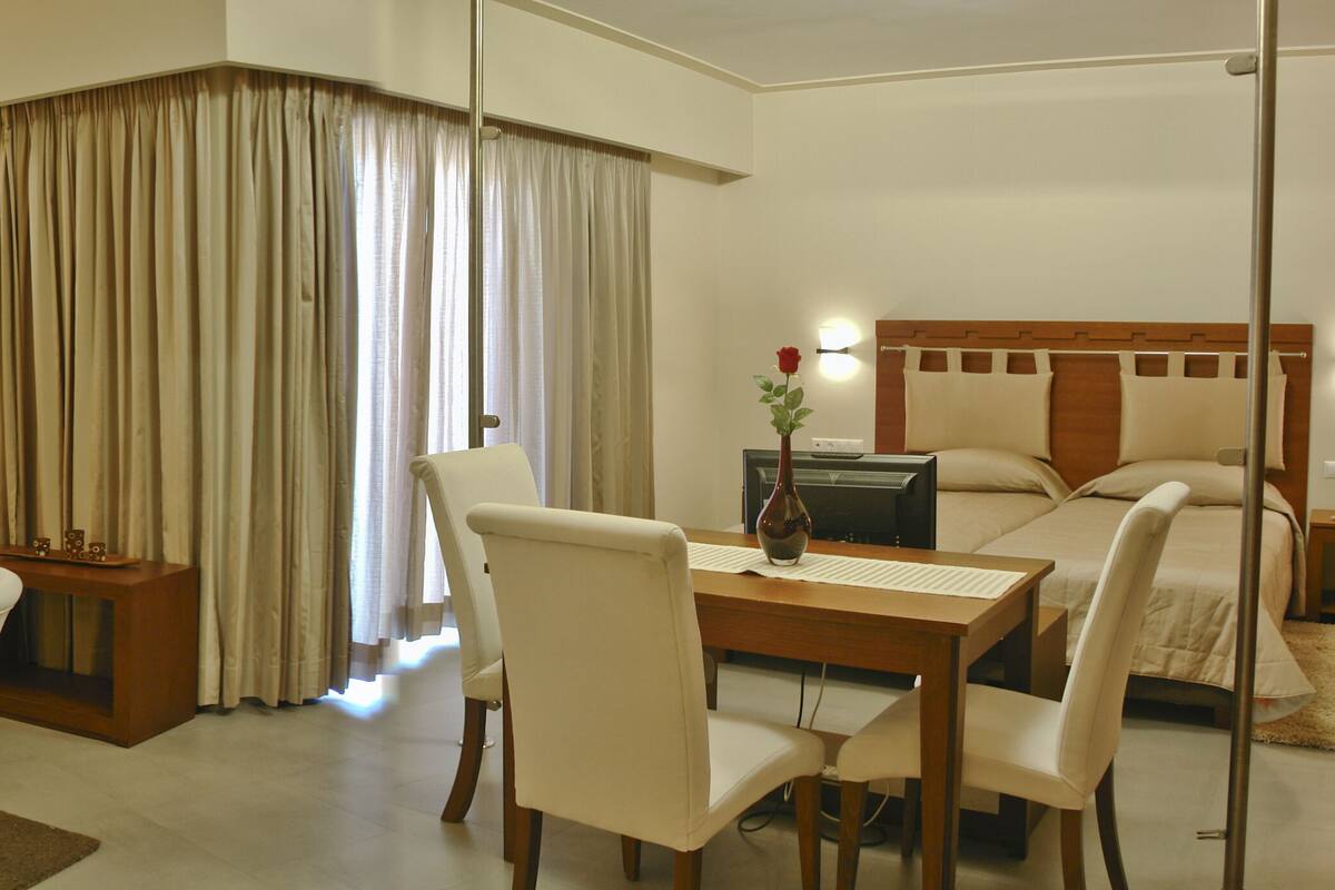 Una habitación de hotel con comedor, cama y televisor.