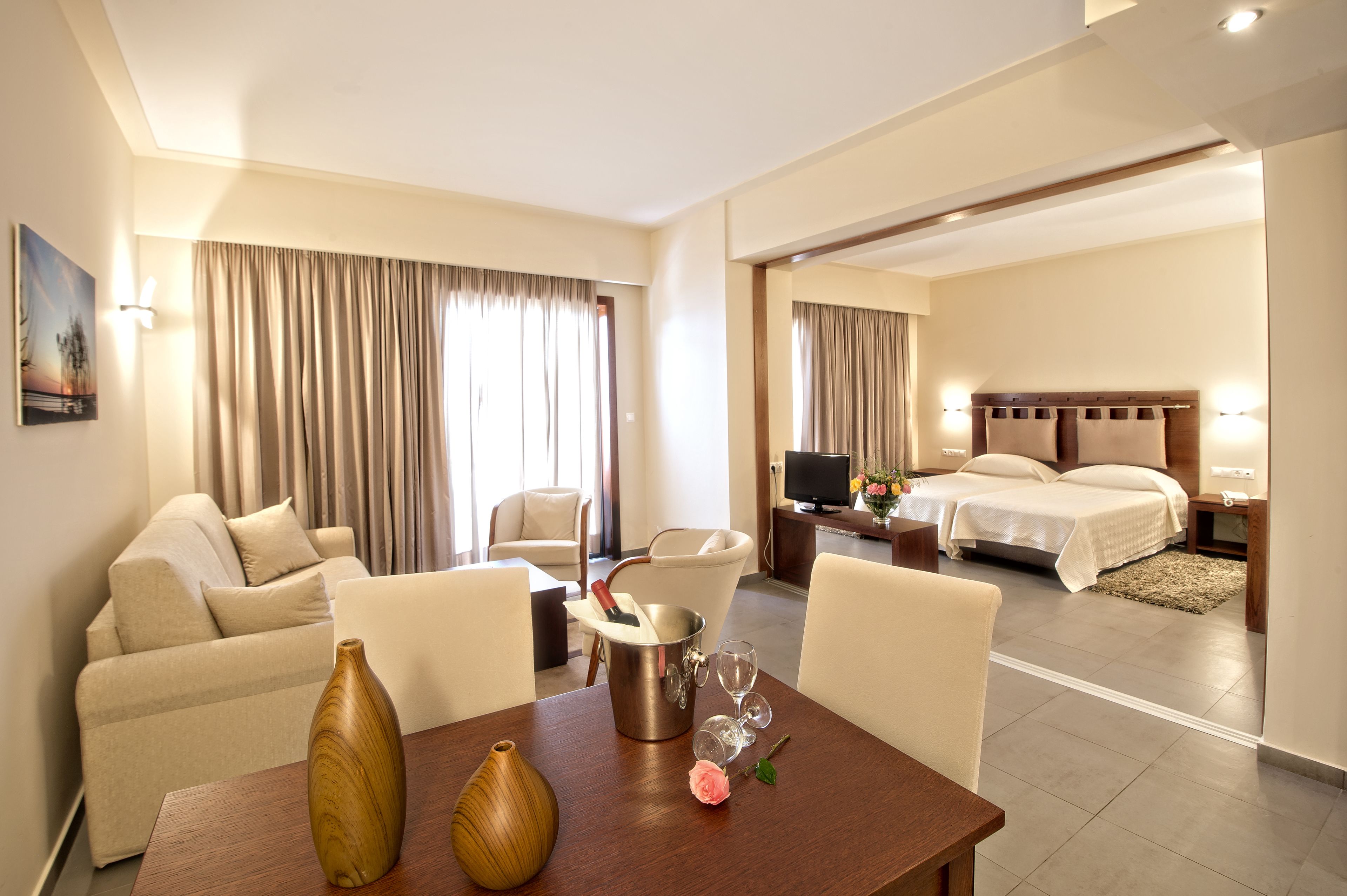 A hotel room with a dining area, a bed, and a television.