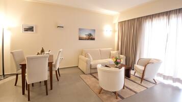 Un salon moderne comprenant un coin repas, un canapé, deux fauteuils, une table basse et un tableau accroché au mur.