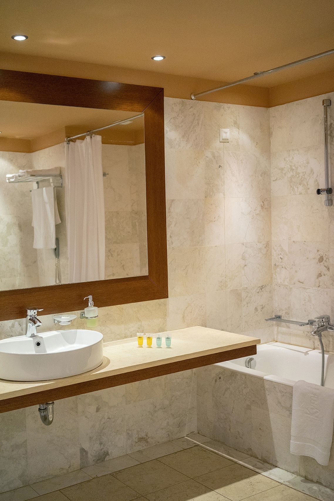 Une salle de bain moderne avec un grand miroir, un lavabo, une baignoire et une douche.