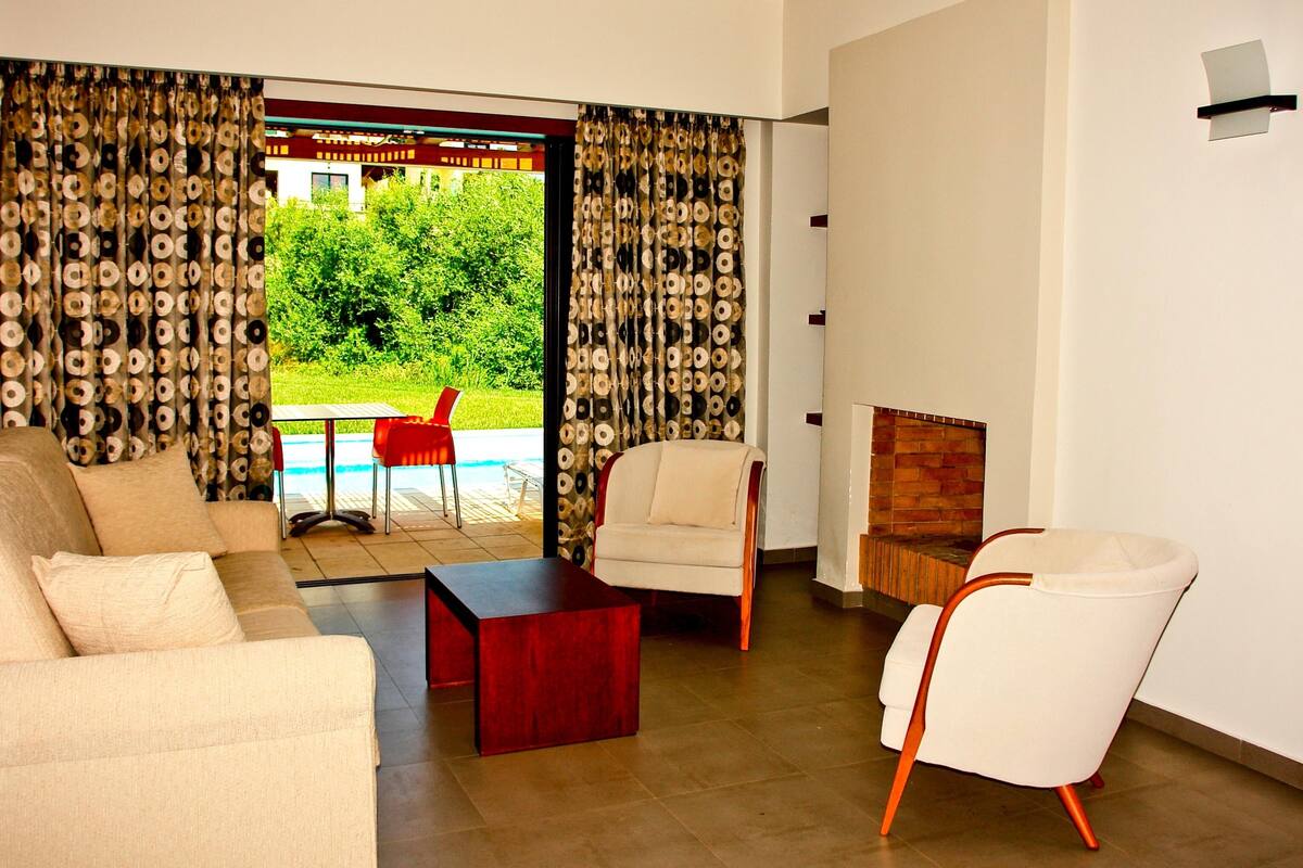 Una sala de estar moderna con un sofá, dos sillones, una mesa de centro y una chimenea.