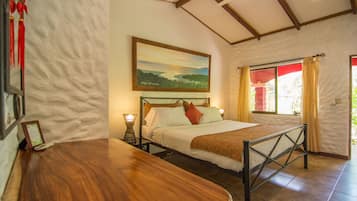 Een slaapkamer met een bed, een houten hoofdbord, bedlampen, een schilderij en een raam met gordijnen.