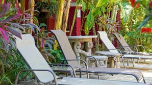 A row of sun loungers with a stone table in a tropical garden setting. - Conchal Hotel (Cabo Velas)