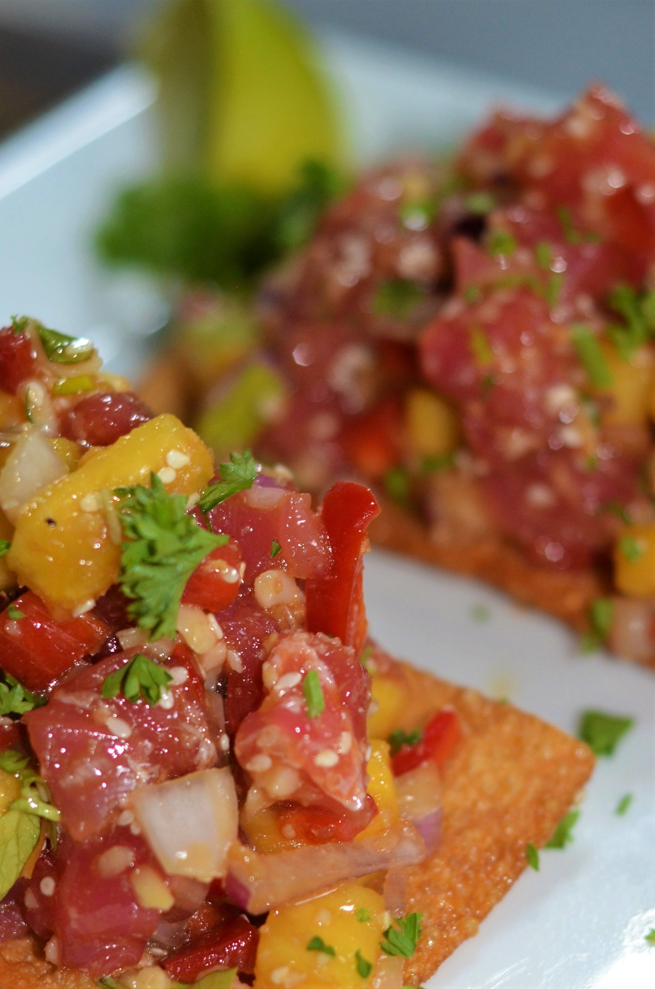 A close-up of a dish with diced meat, diced mango, and chopped onions, garnished with parsley.