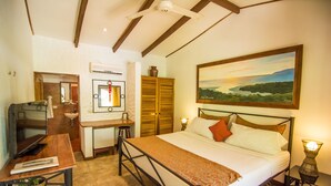 A bedroom with a bed, bedside table, lamp, and a painting on the wall. - Conchal Hotel (Cabo Velas)