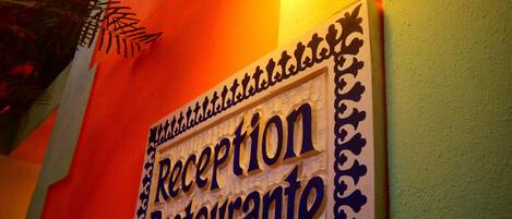 A reception sign with a decorative border and a light fixture above it.