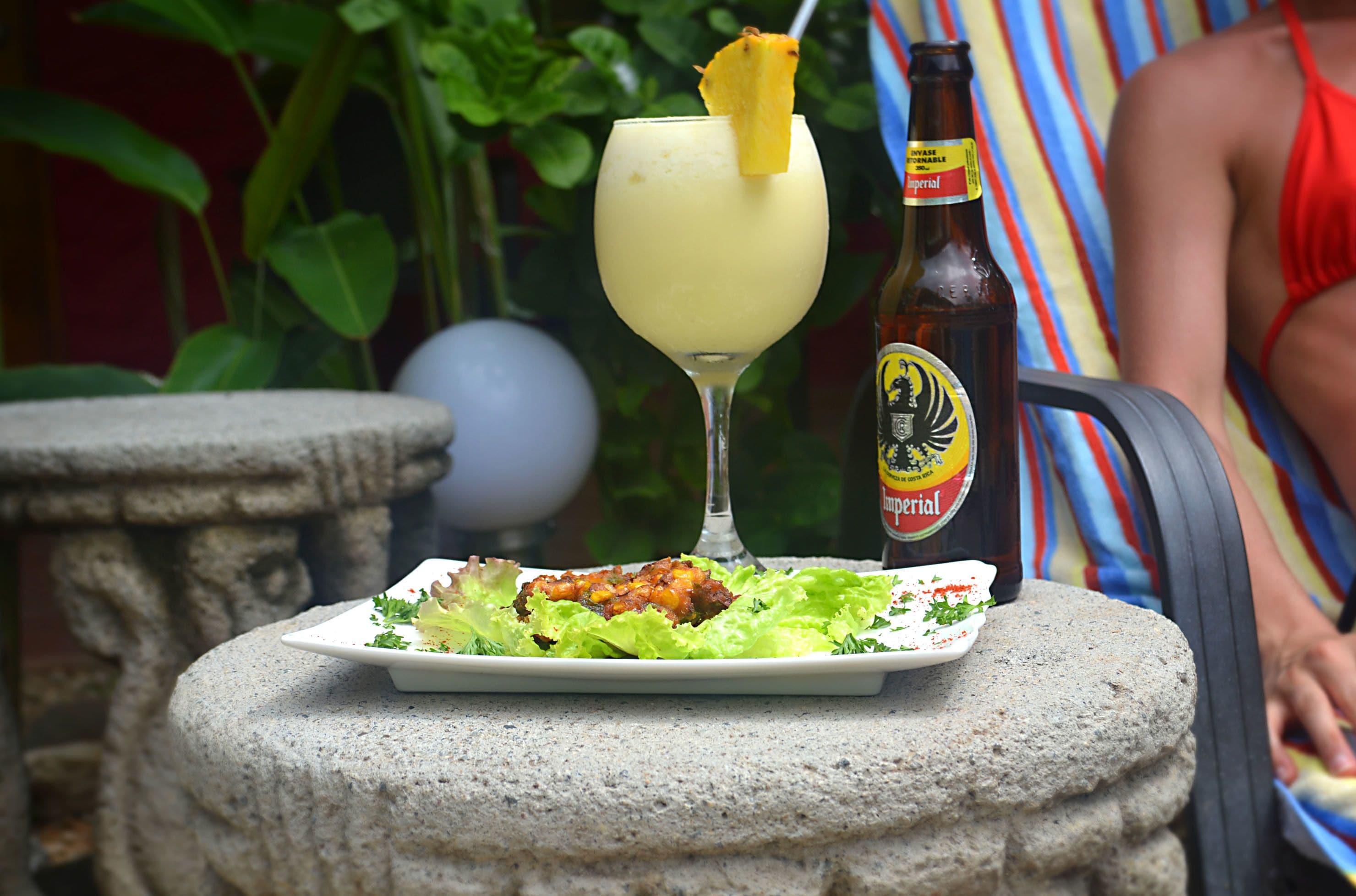Una mesa con un plato de comida, una bebida en un vaso y una botella de cerveza.