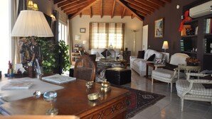 A spacious living room with a high wooden ceiling, a large wooden dining table, and comfortable seating. - Welcome Inn Nerja (Nerja)