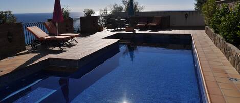 Una piscina sul tetto con acqua cristallina, lettini prendisole e vista sul mare.